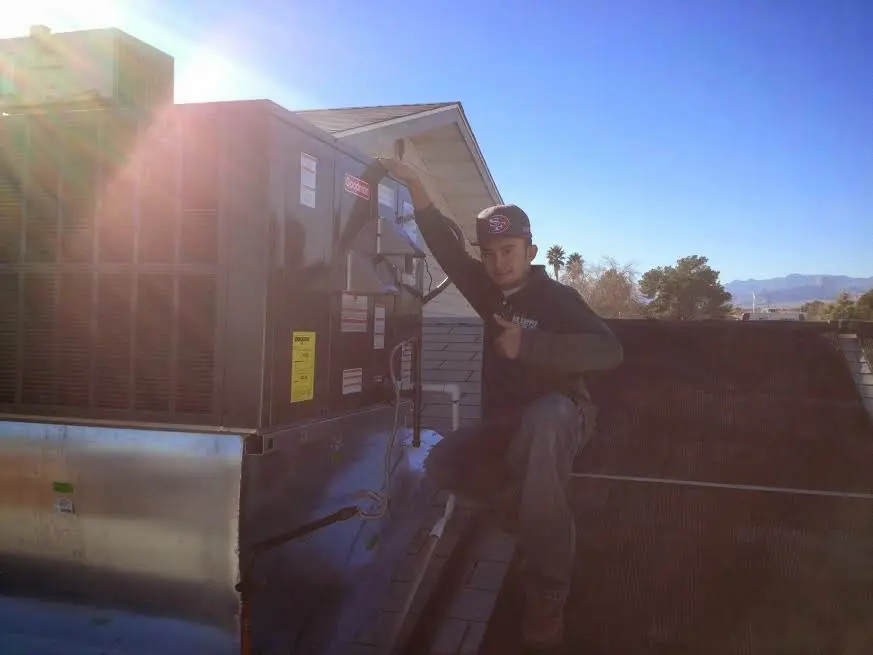 HVAC technician performing Air Duct Repair on a rooftop unit in Alma